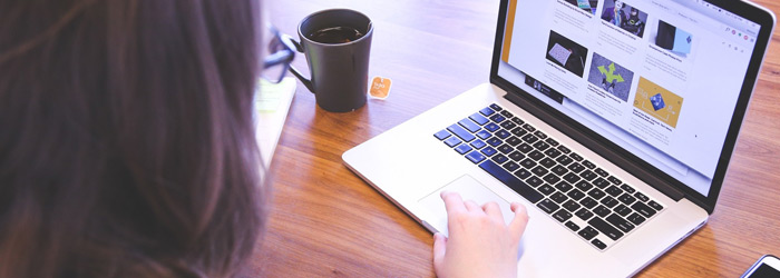 Laptop auf Holztisch mit schwarzer Teetasse